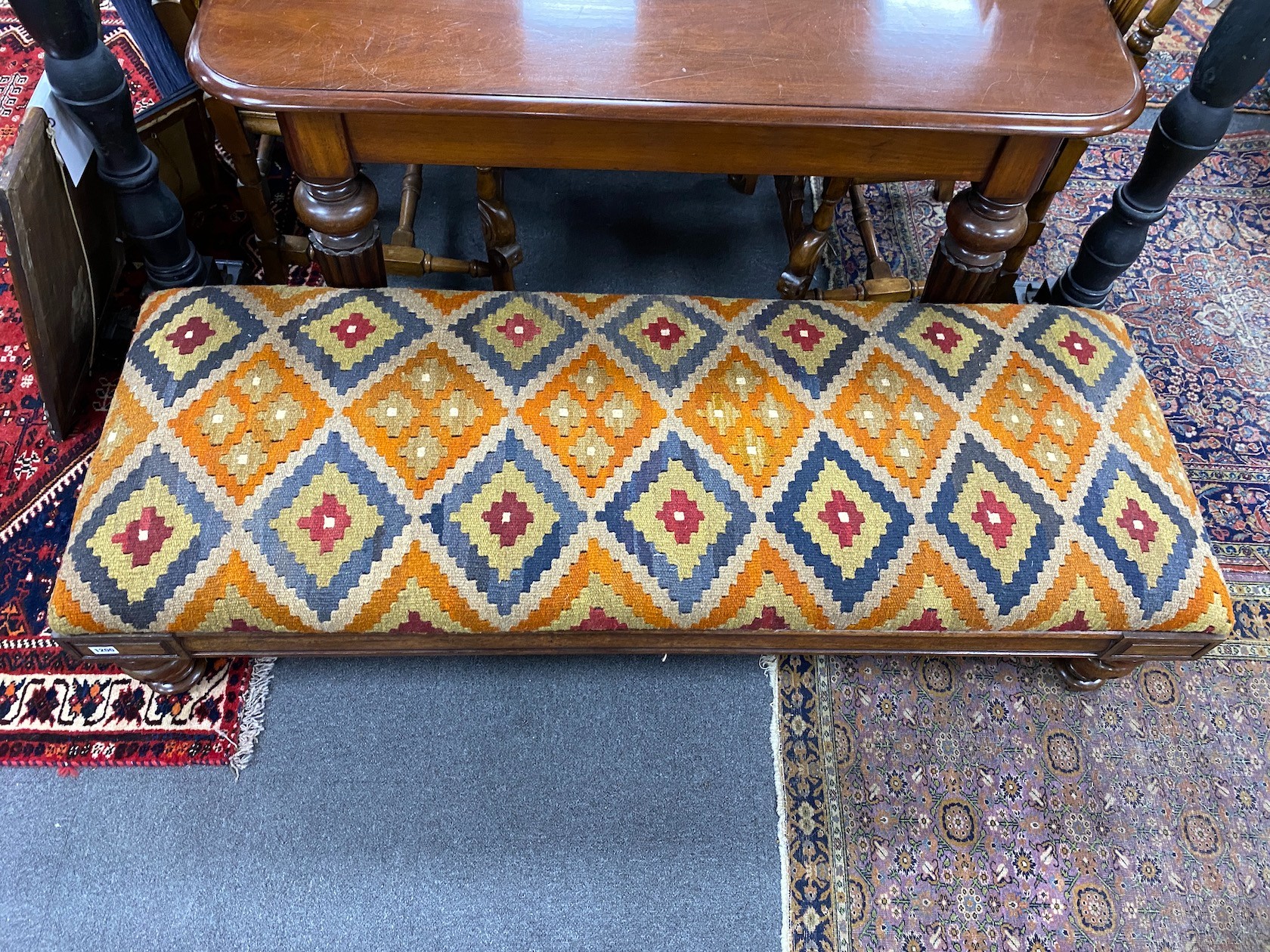 A William IV mahogany stool with polychrome kilim upholstered seat width 164cms, depth 59cms, height 36cms. (Adapted).